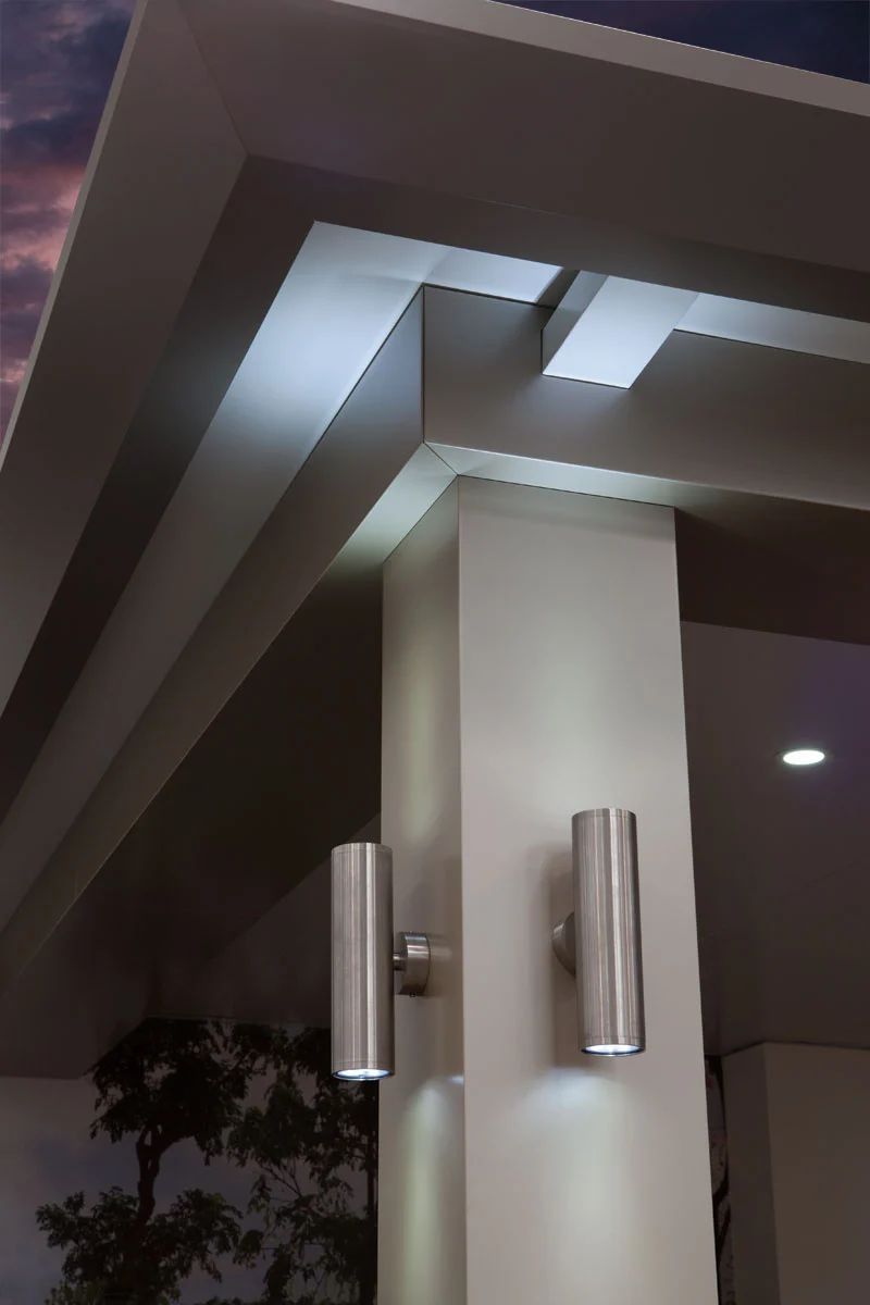 Modern building entrance with a white column, metal wall lights, and dark evening sky