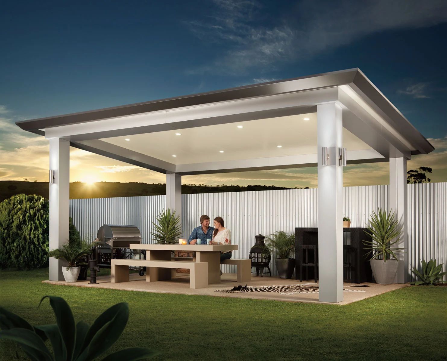 Modern outdoor patio pavilion with white columns, dining table, seating, and warm sunset lighting