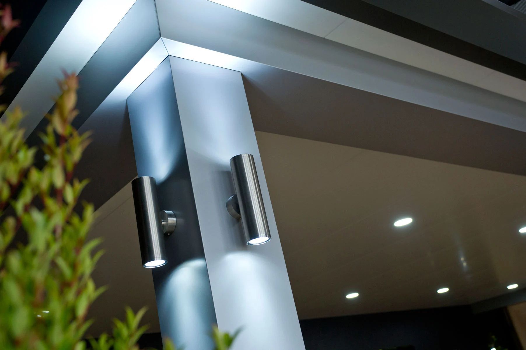 Modern building entrance with blue-lit pillars and recessed ceiling lights at night