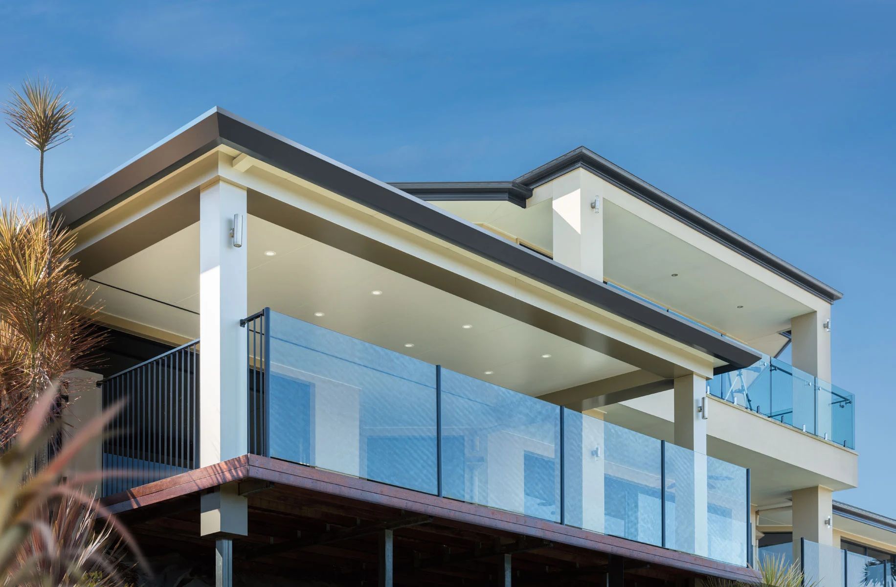 Modern house with glass balcony and sloped roof under a clear blue sky