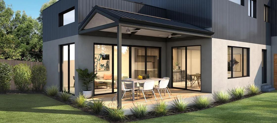 Modern two-story black house with large glass doors and a patio overlooking a green lawn