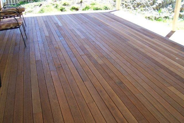 Wooden deck with long planks, sunlight, and a chair on the left side