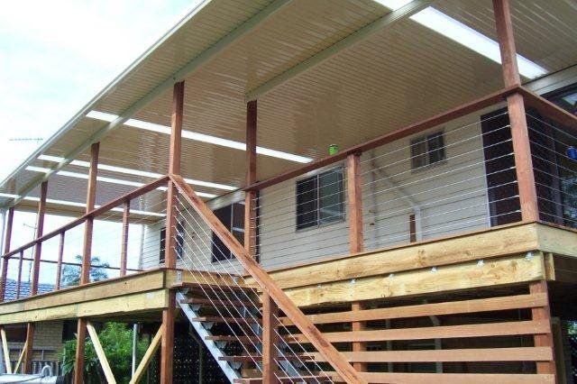 Raised wooden house with porch, stairs, and corrugated metal roof under construction