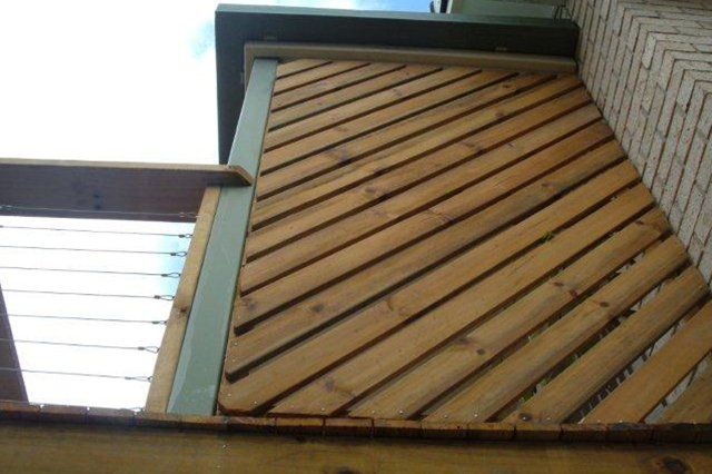Wooden slat wall corner with teal trim beneath a white translucent roof panel.