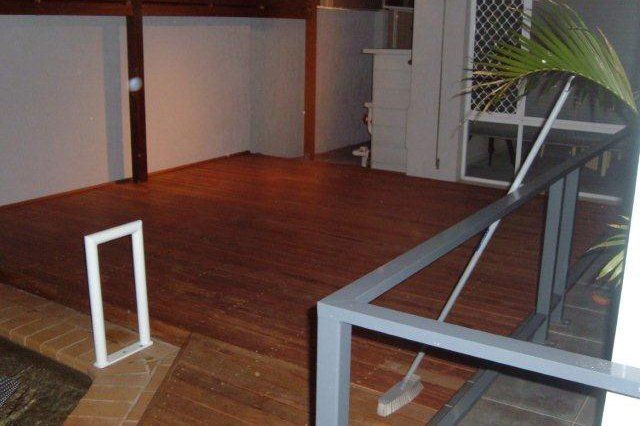 Indoor wooden deck with white railings and a potted plant in the corner.