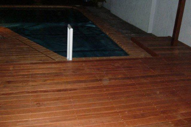 Indoor wooden floor with a dark rug and a white post or marker near the center