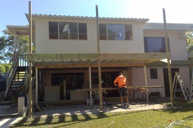 Two-story house under construction with workers and scaffolding in front yard