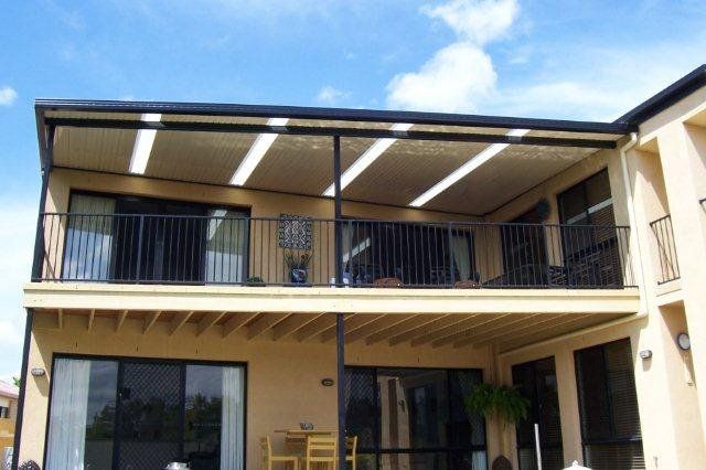 Two-story beige house with a covered balcony and black railings