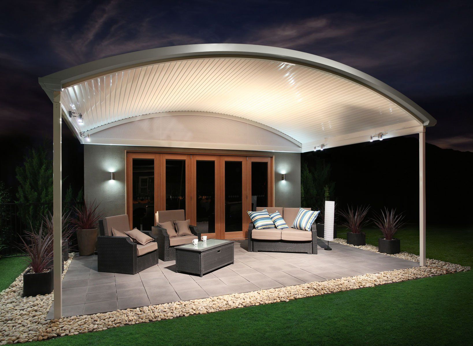 Outdoor patio with curved roof, seating area, and warm lights at night