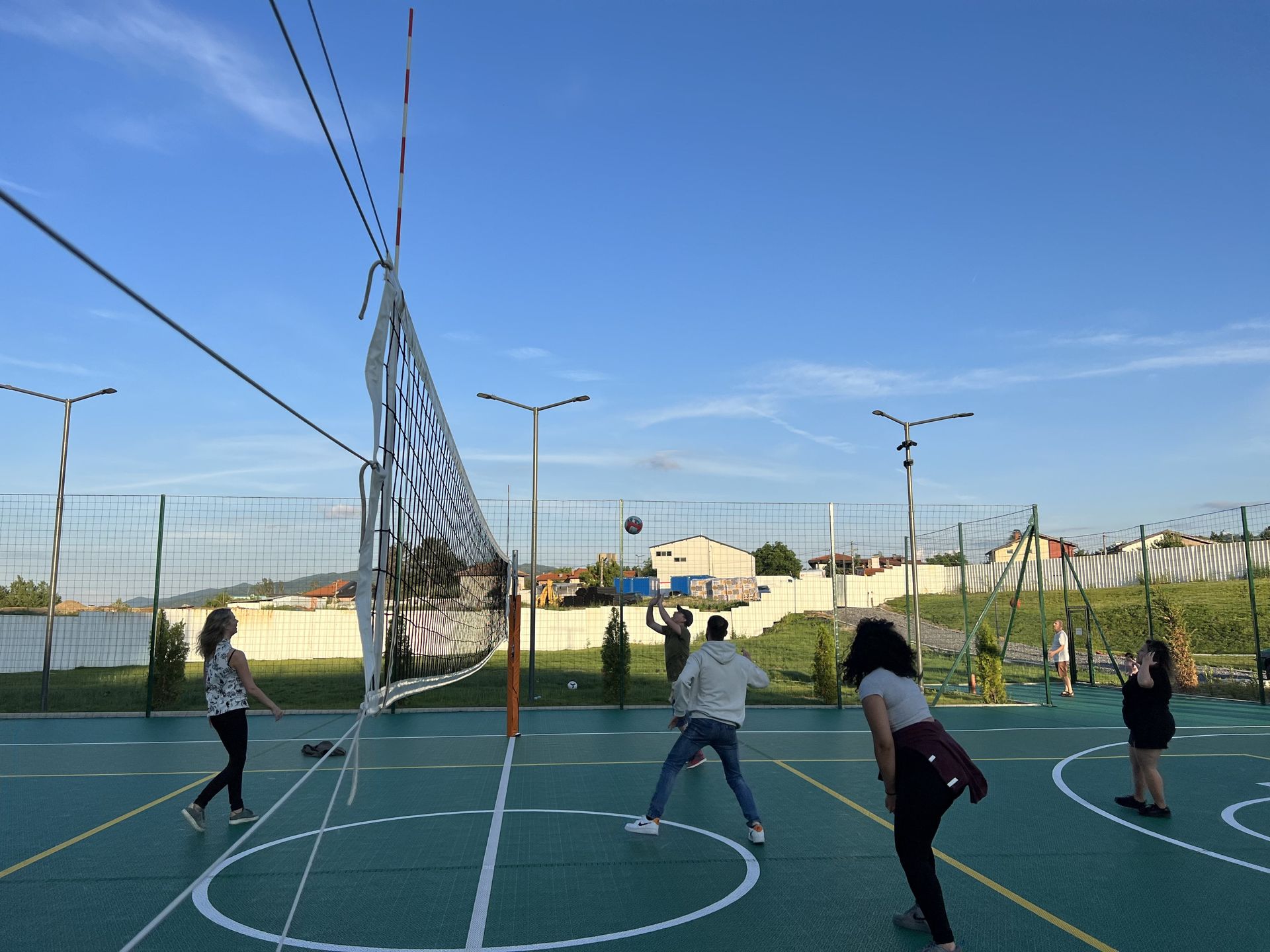 People playing volleyball on an outdoor court under a blue sky