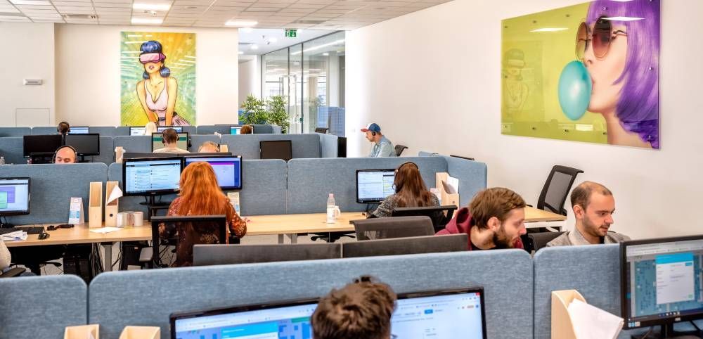 Open office with employees at computers and colorful wall art in the background