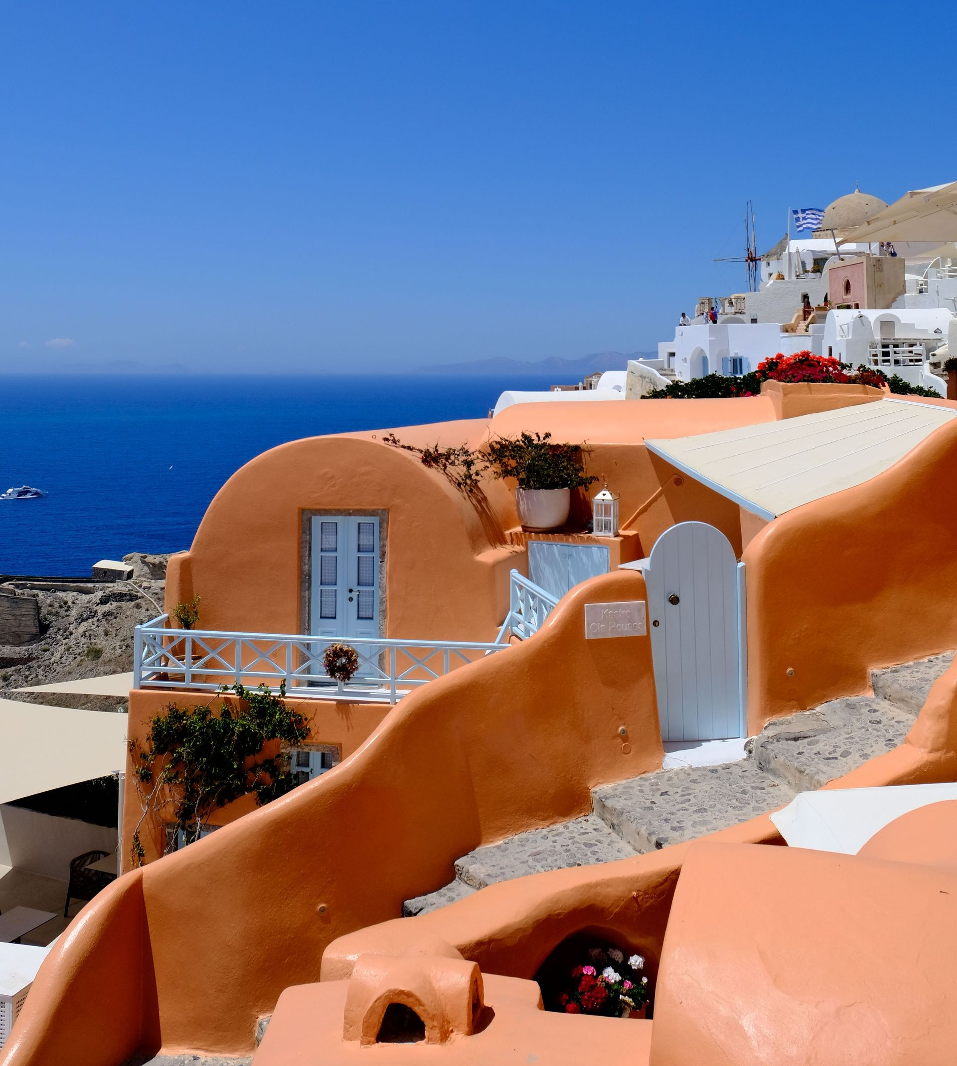 White and terracotta cliffside buildings overlooking a deep blue sea under a clear sky