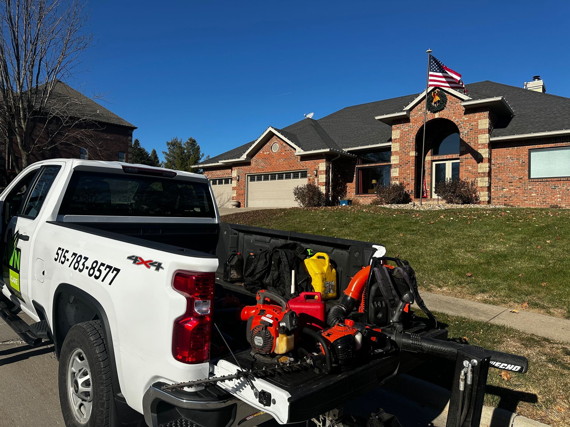 A white truck is parked in front of a brick house.