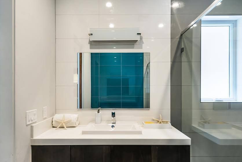 Modern bathroom vanity with mirror, white countertop, and glass shower enclosure