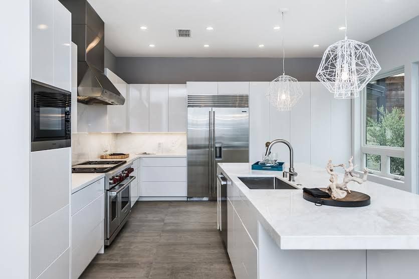 Modern white kitchen with stainless steel appliances, island sink, and pendant lights