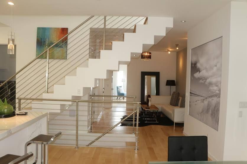 Modern loft interior with floating staircase, glass railing, and hardwood floors