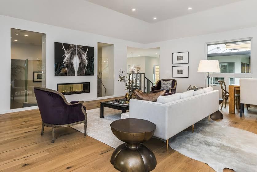 Modern living room with white sofa, purple chair, wall art, fireplace, and hardwood floors