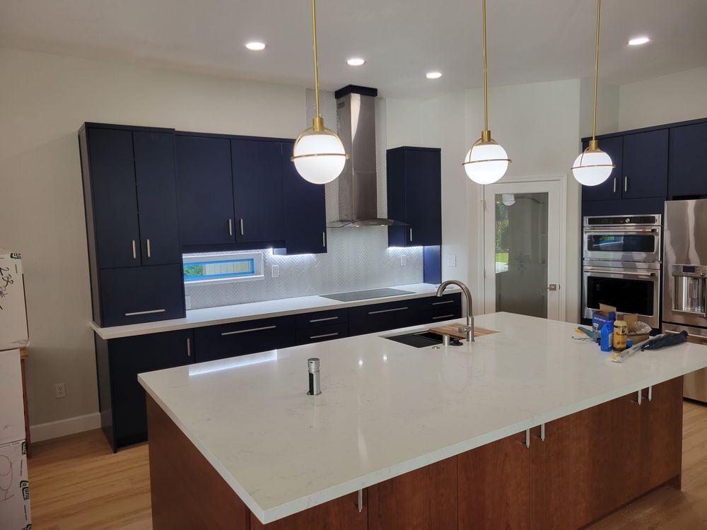 Modern kitchen with dark cabinets, white island countertop, and pendant lights