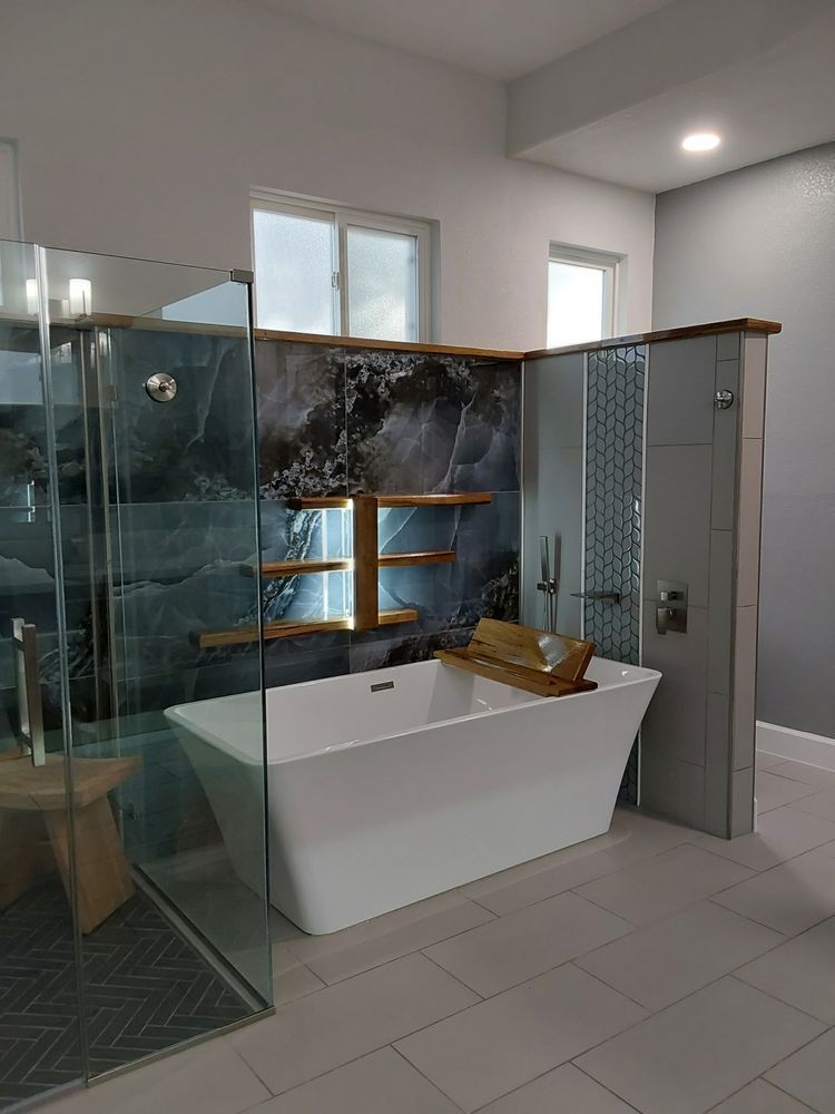 Modern bathroom with a glass shower, white bathtub, and dark stone accent wall