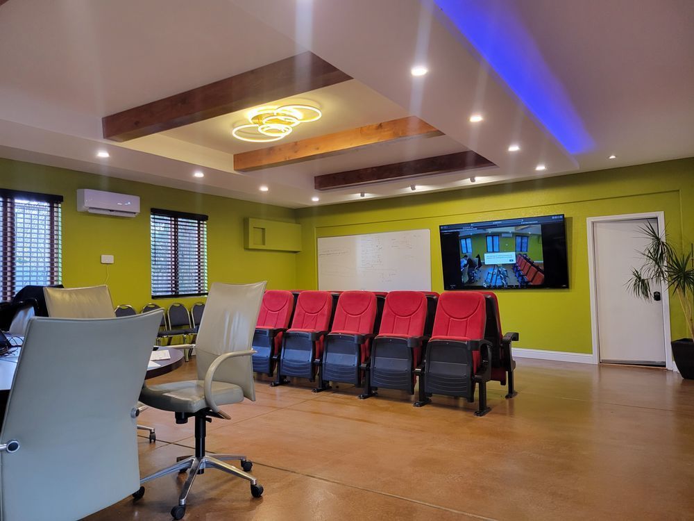 Modern waiting room with chairs, wall TV, and green walls under recessed lighting