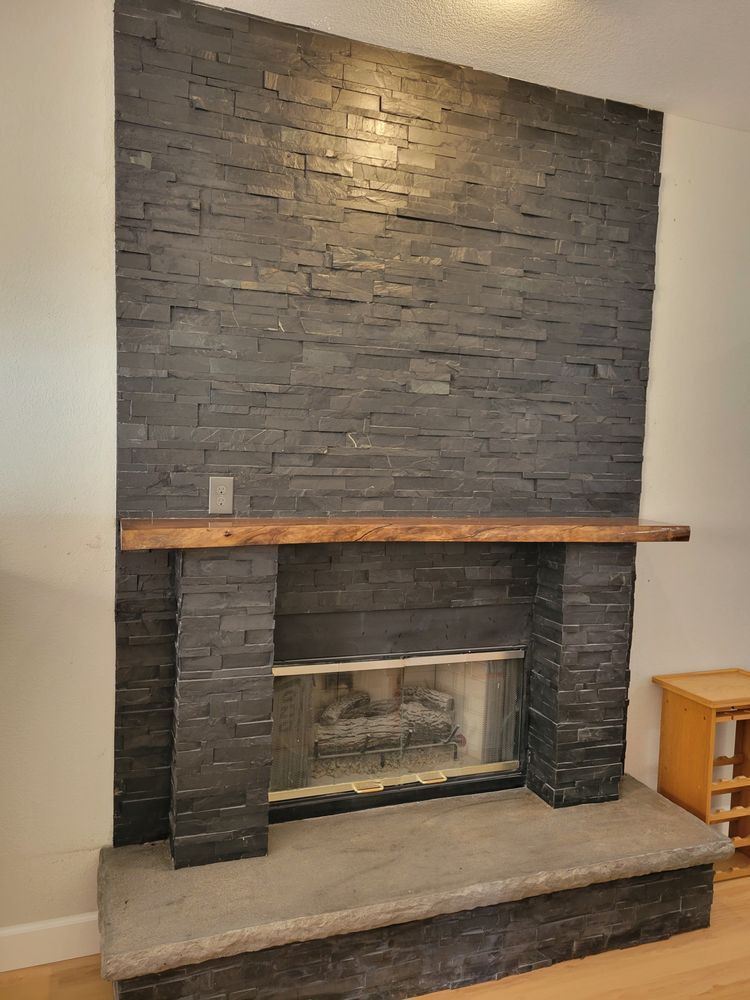 Dark brick fireplace with a wooden mantel and stone hearth in a room