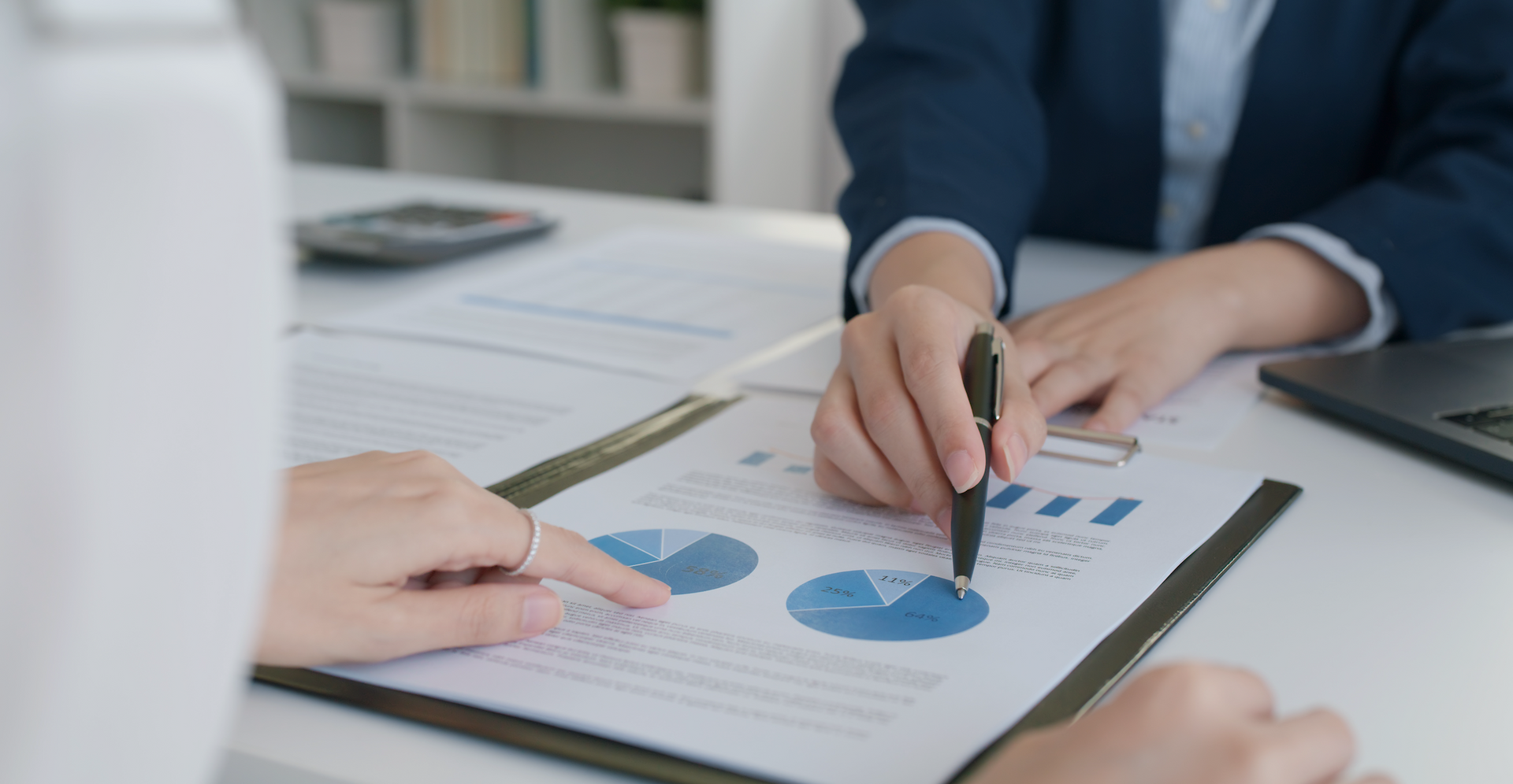 A woman is pointing at a pie chart on a clipboard.