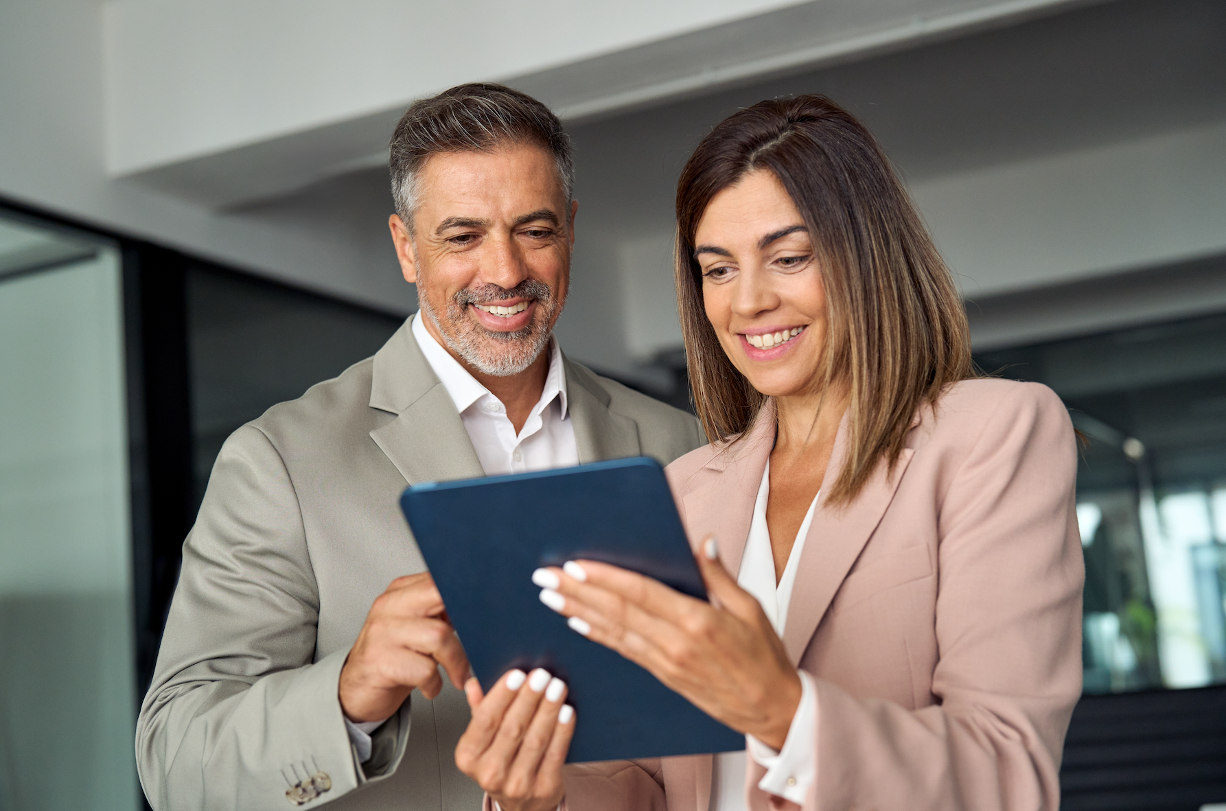 A man and a woman are looking at a tablet together.