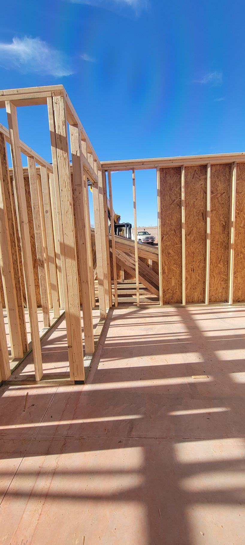 The wooden framing of a building under construction against a clear blue sky.