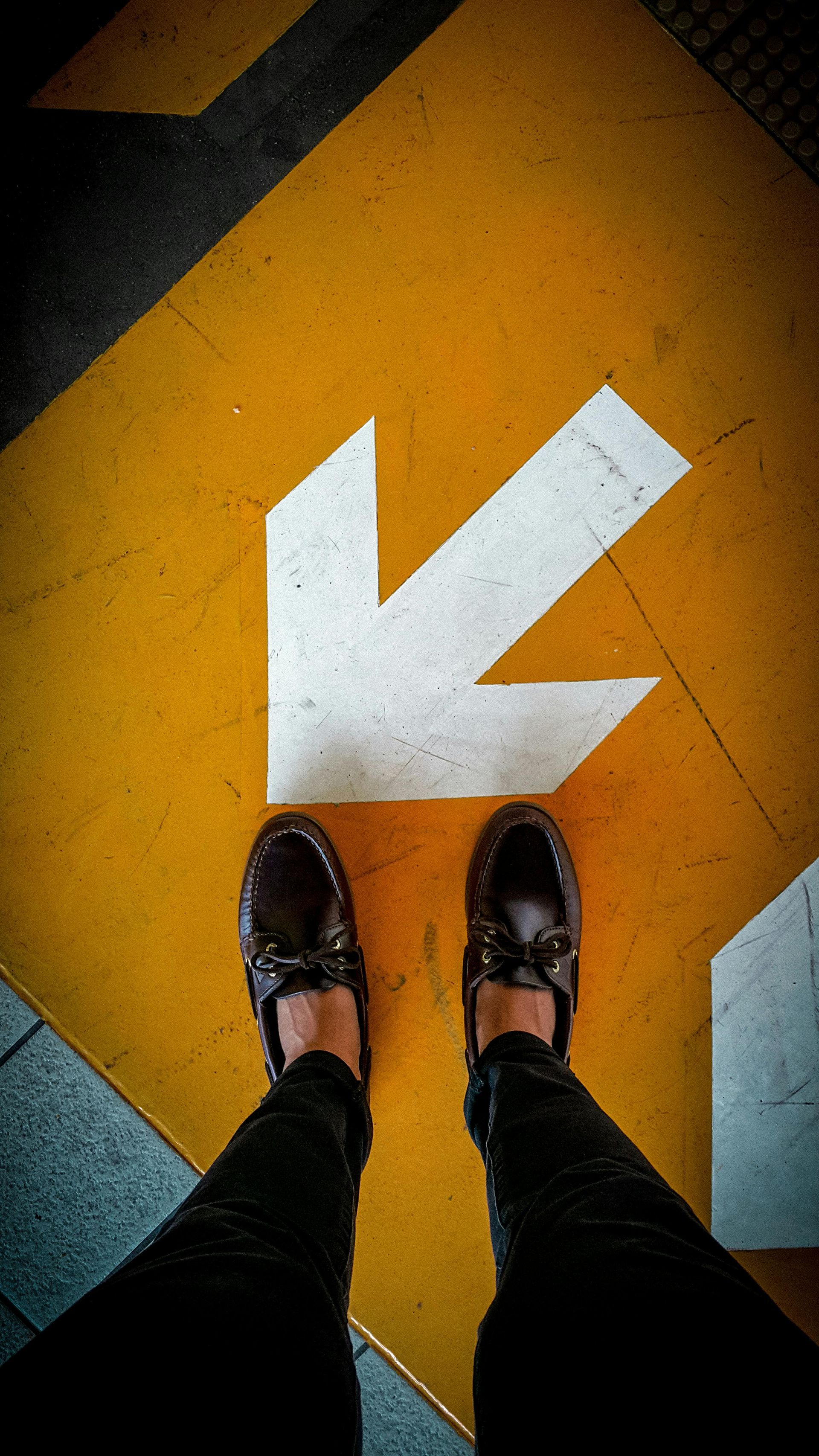 Schoenen staan ​​op een oranje vloer met een grote witte pijl die naar links wijst.