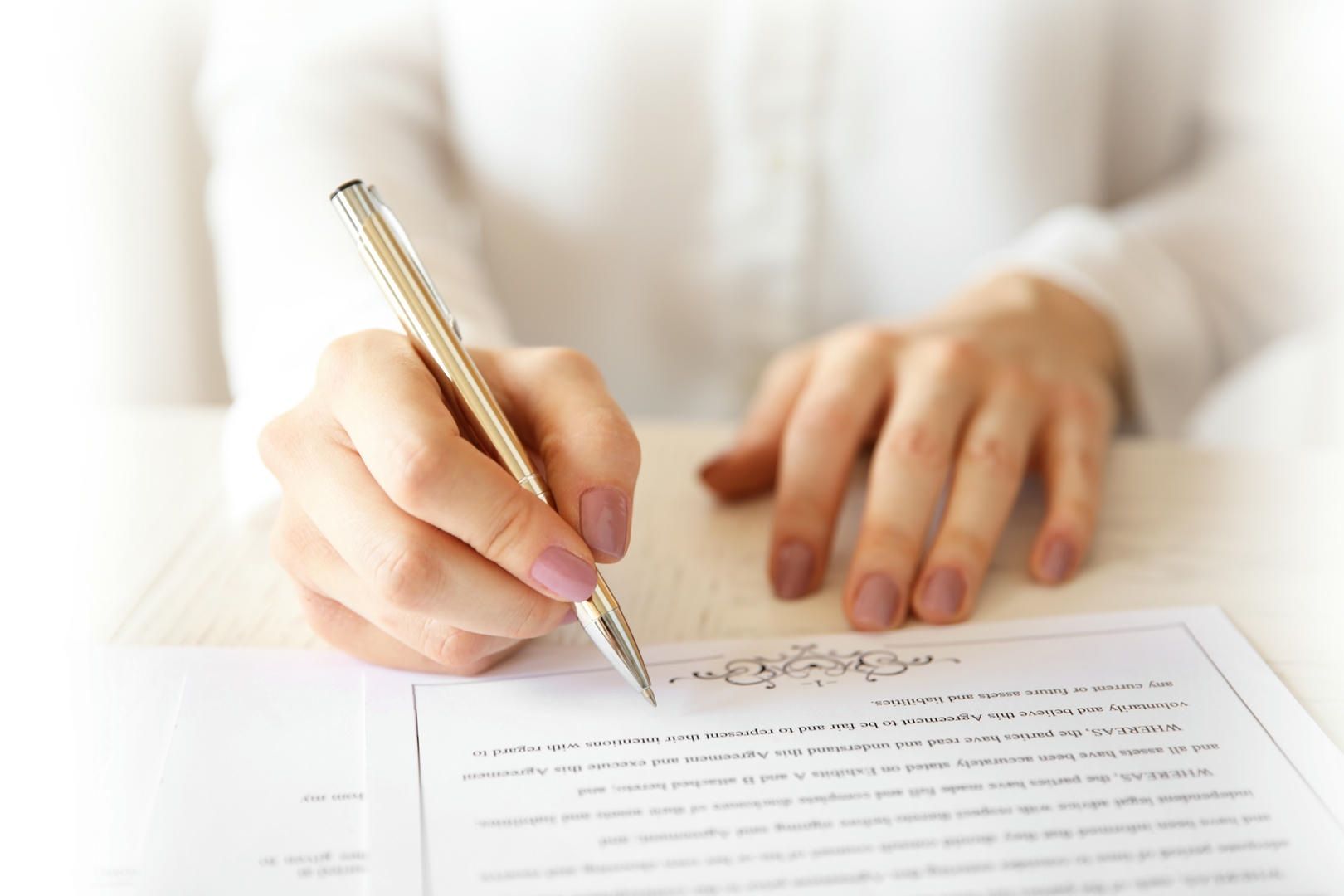 A woman is writing on a piece of paper with a pen.