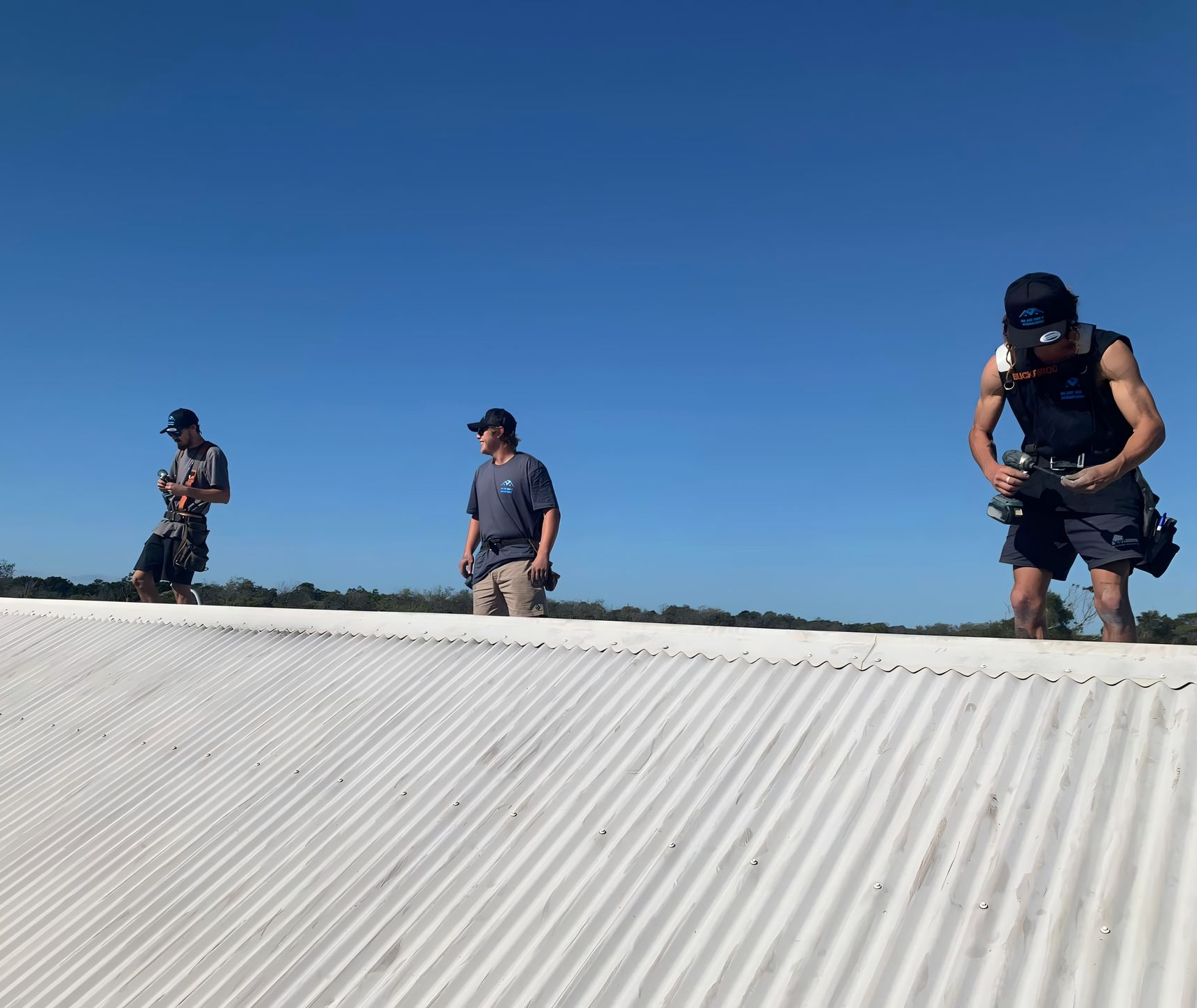 Three men are standing on a roof while working on a sunny day — Blue Sky Roofing NSW In Kingscliff, NSW