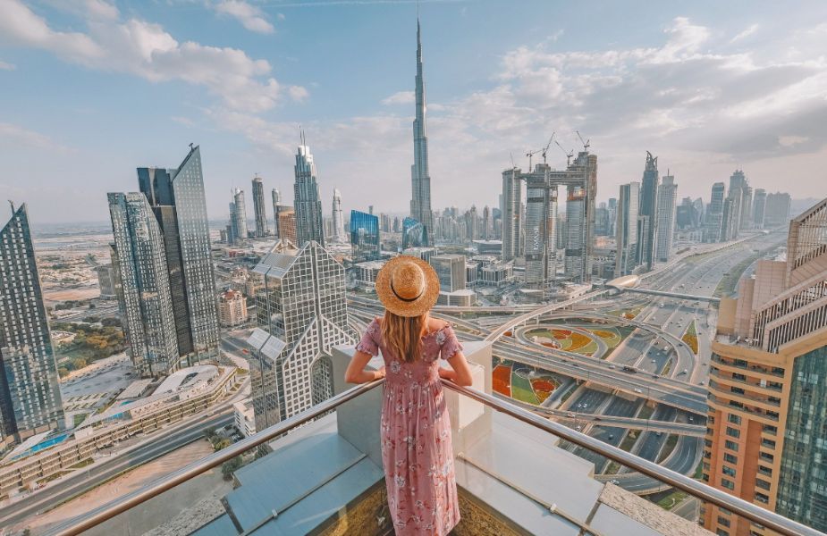 A woman is standing on a balcony overlooking a city skyline.