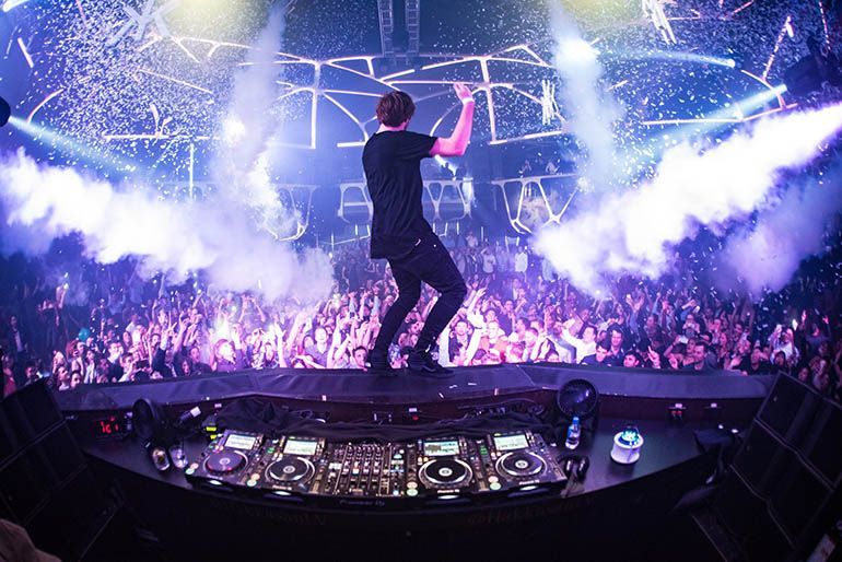 A man is standing on a stage in front of a crowd at a concert.