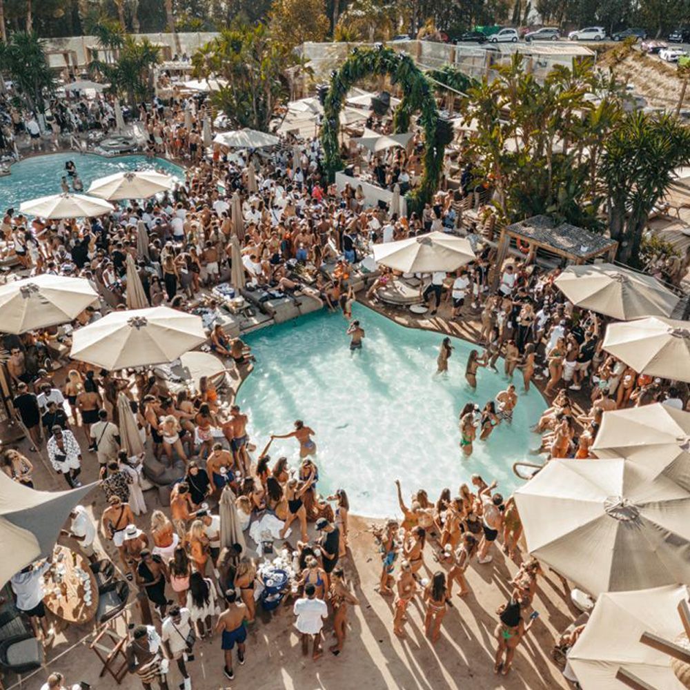 An aerial view of a large pool filled with people and umbrellas.