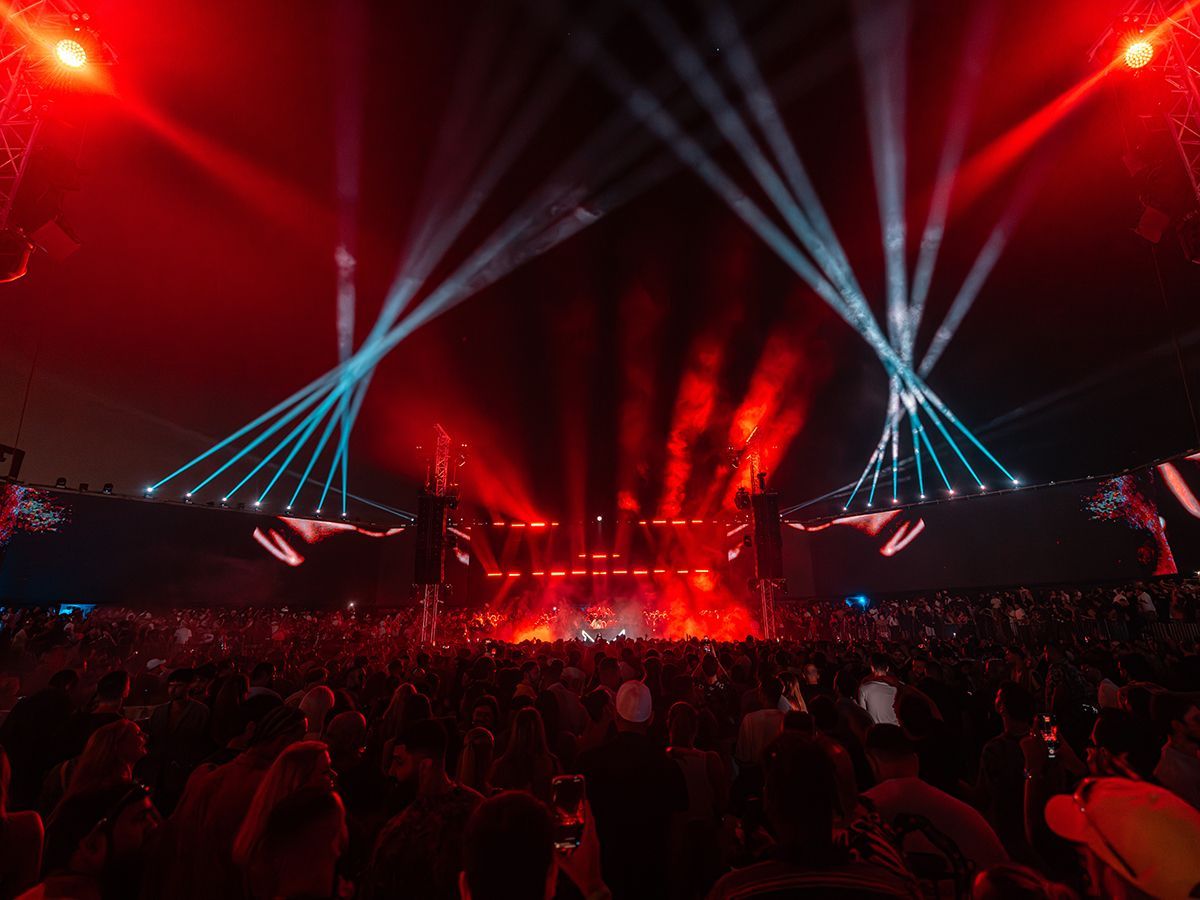 A crowd of people are standing in front of a stage at a concert.