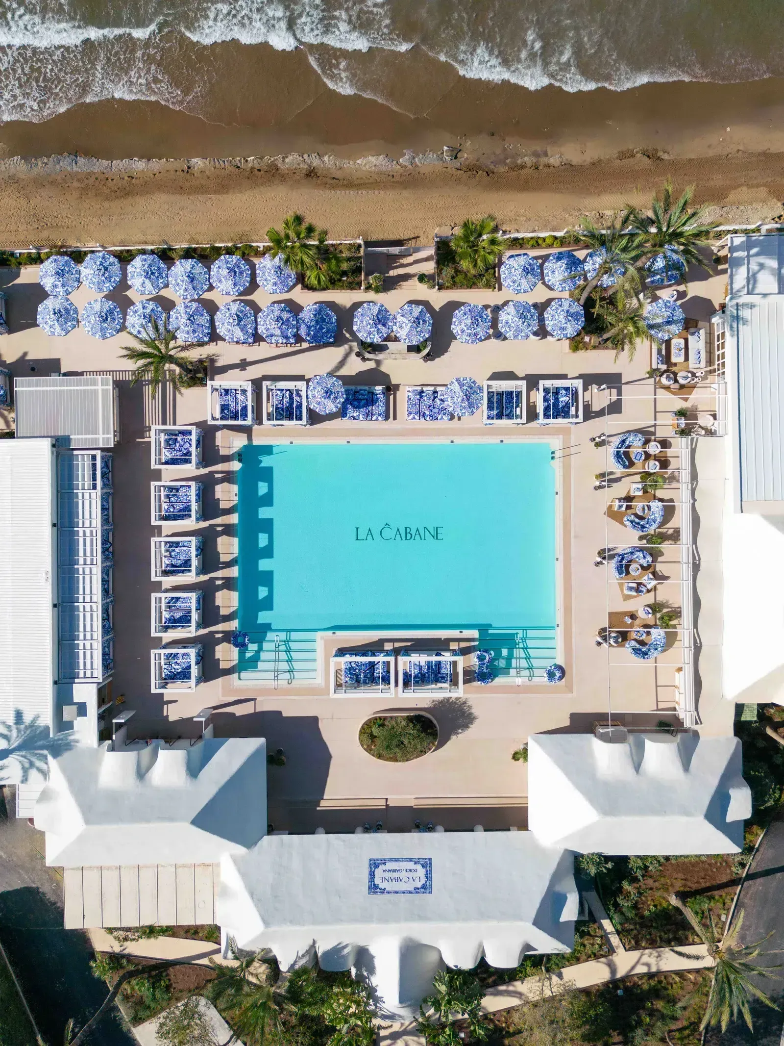 An aerial view of a large swimming pool surrounded by chairs and umbrellas.