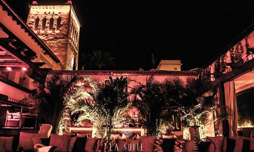 A building with a tower in the background is lit up at night