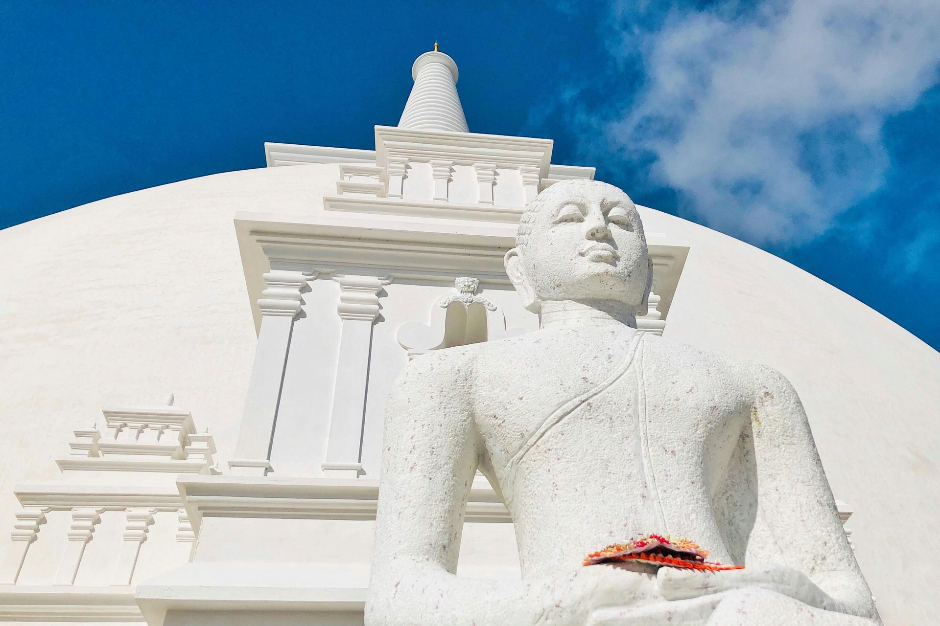 A white statue of a man sitting in front of a building