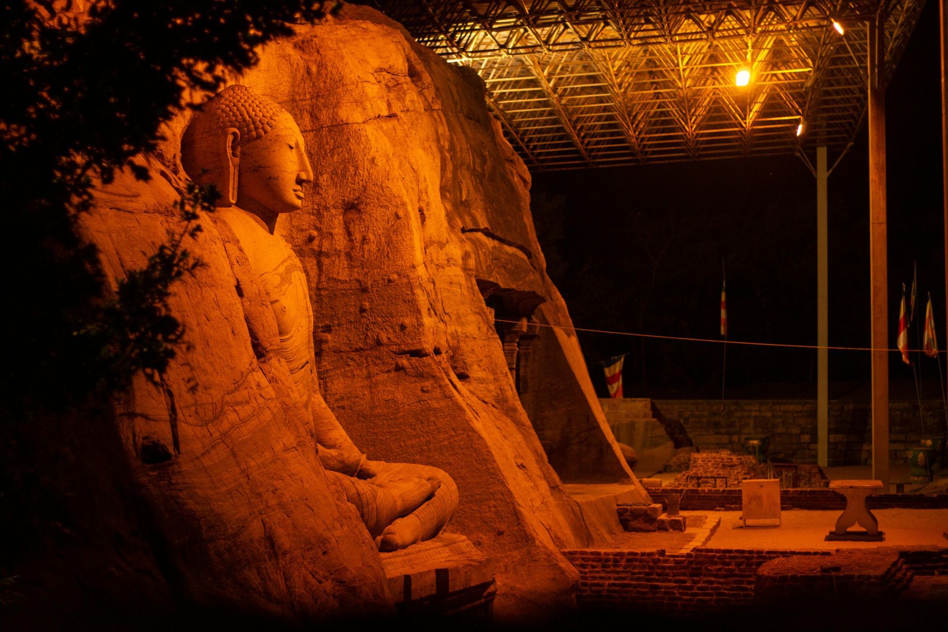A statue of a man sitting on a rock at night