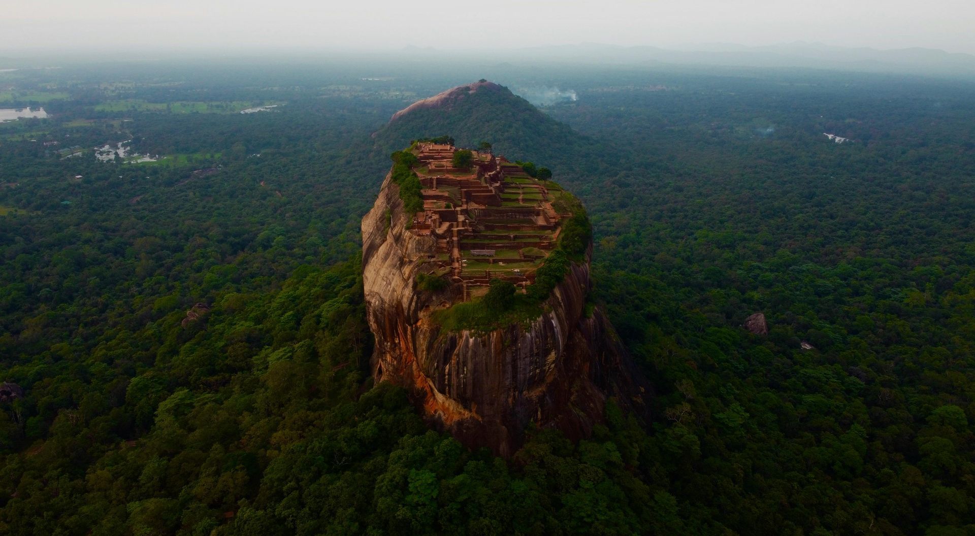 An aerial view of a large rock formation in the middle of a forest.