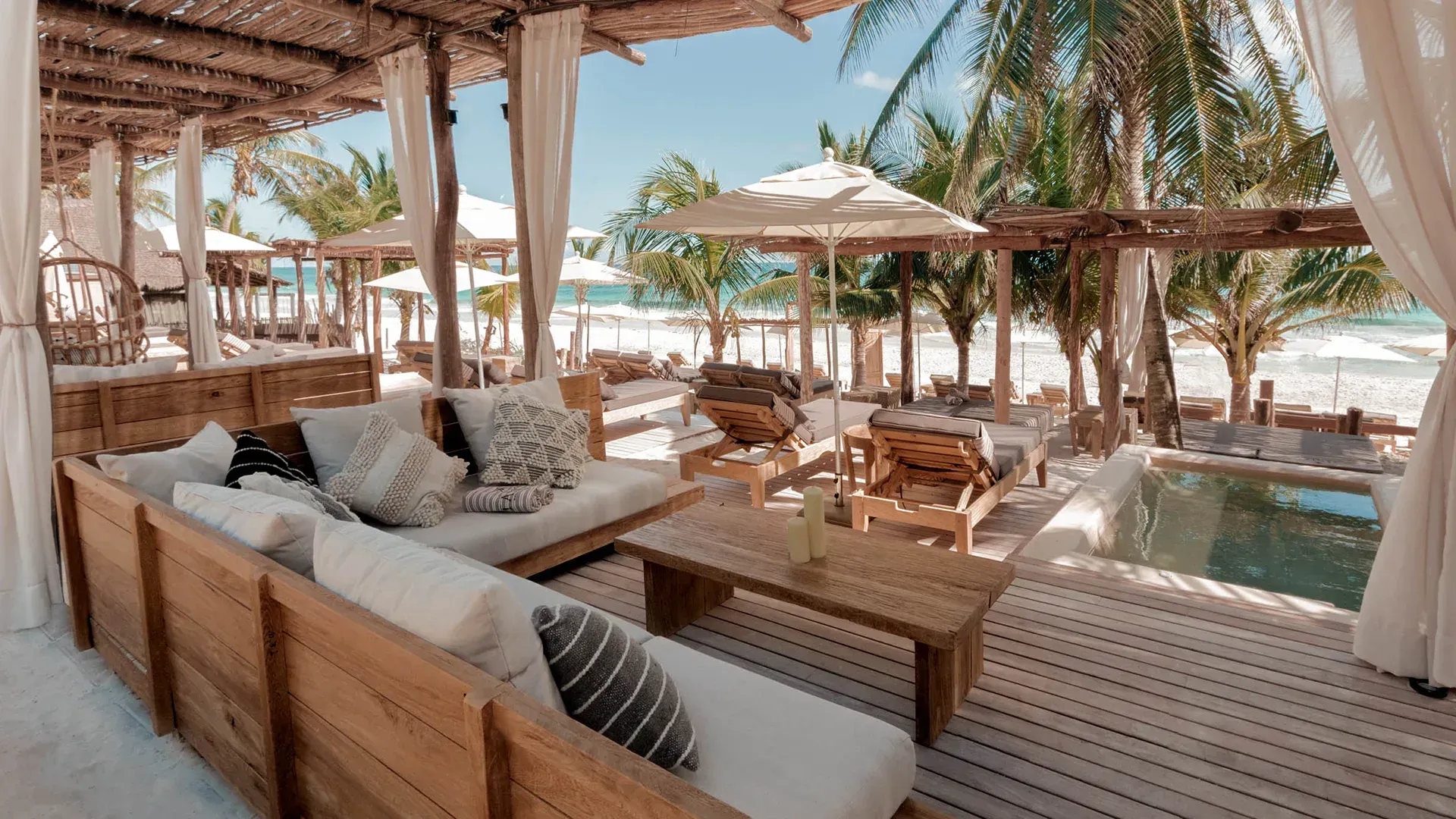 A patio with a lot of furniture and umbrellas and a pool.