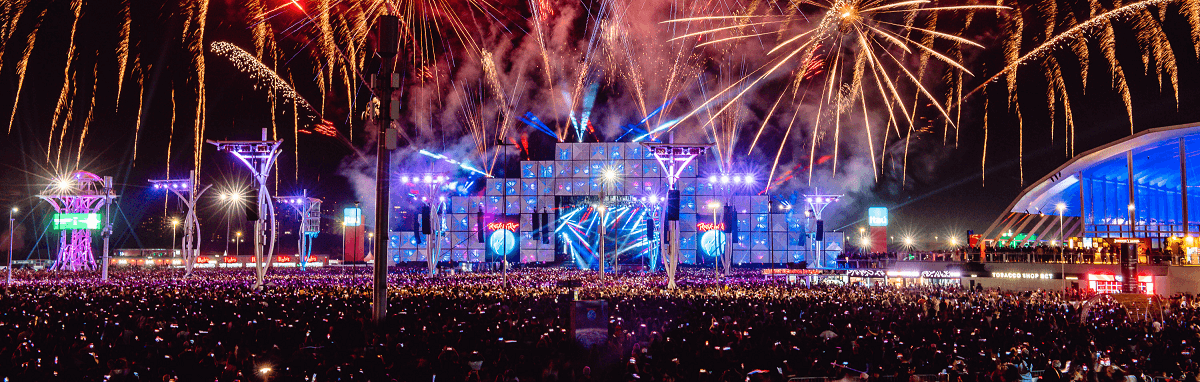 A crowd of people are watching fireworks at a concert.