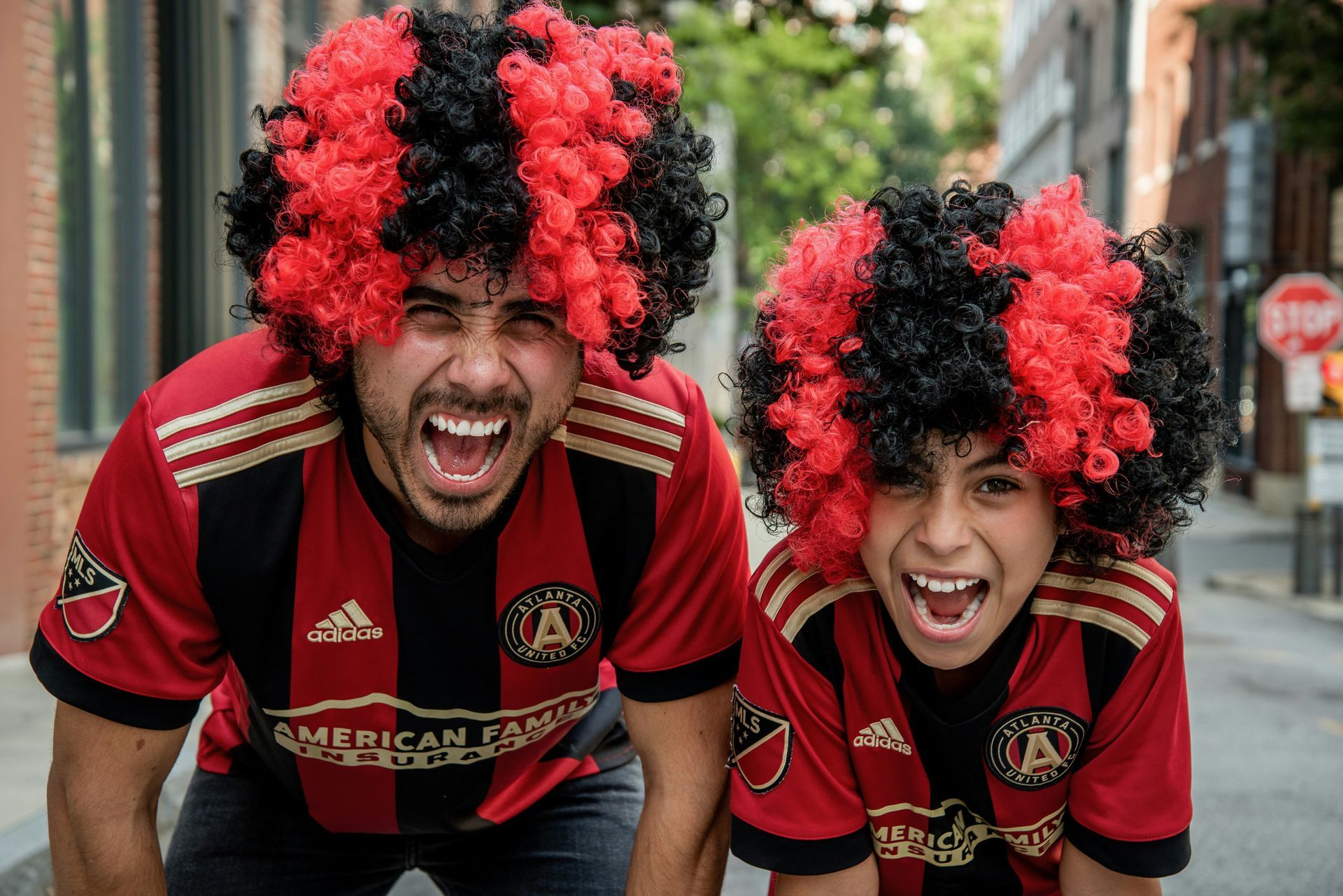 A man and a boy are wearing red and black wigs.