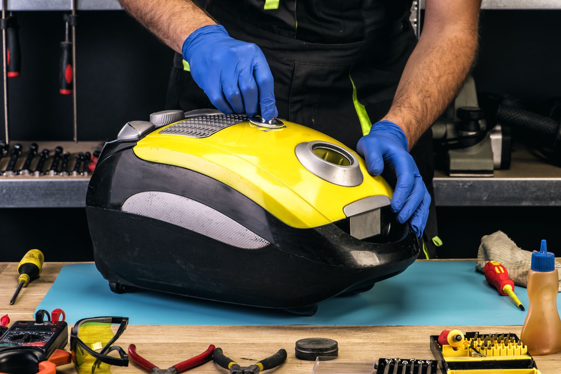 Technician repairing a yellow and black appliance on a workbench with tools