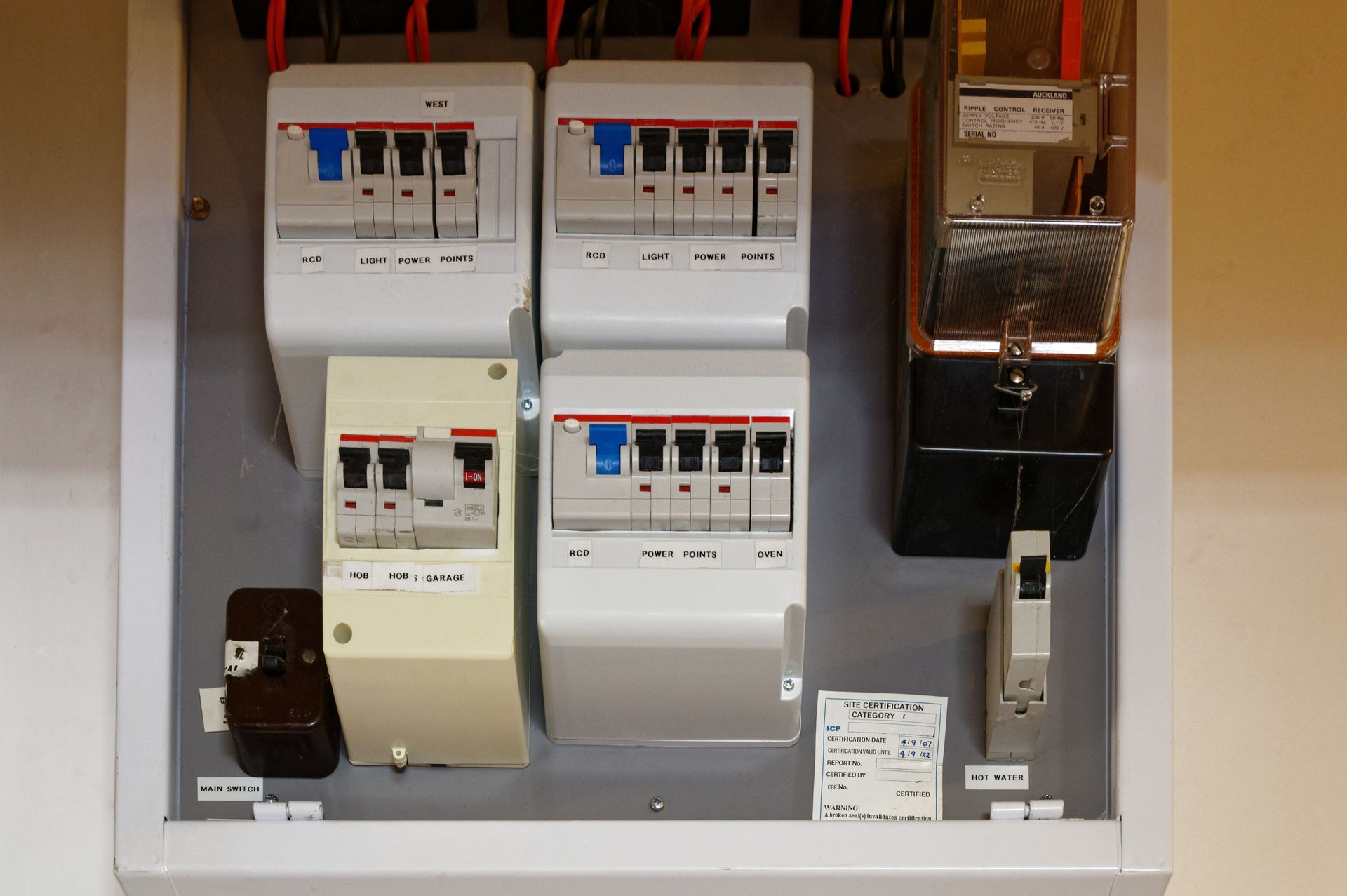 Electrical breaker panel with several switches and a meter inside a gray cabinet