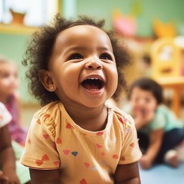 A baby is sitting on the floor with his mouth open and smiling.