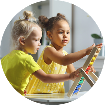 Two little girls are playing with a wooden abacus.