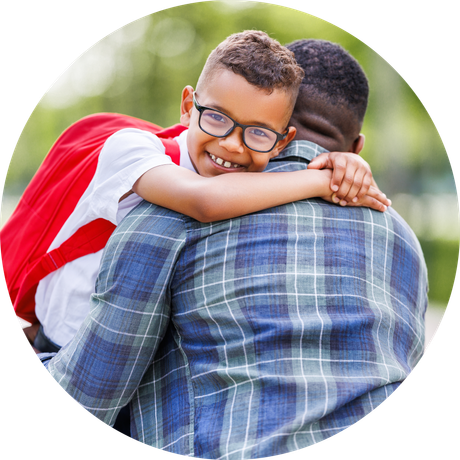 A young boy with glasses is hugging his father.