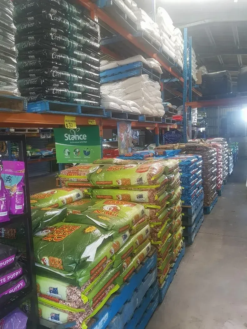 Rows of Stacked Pet Food Bags on Blue Pallets in a Store Aisle — NQ Stockfeeds & Farm Supplies In Mareeba, QLD