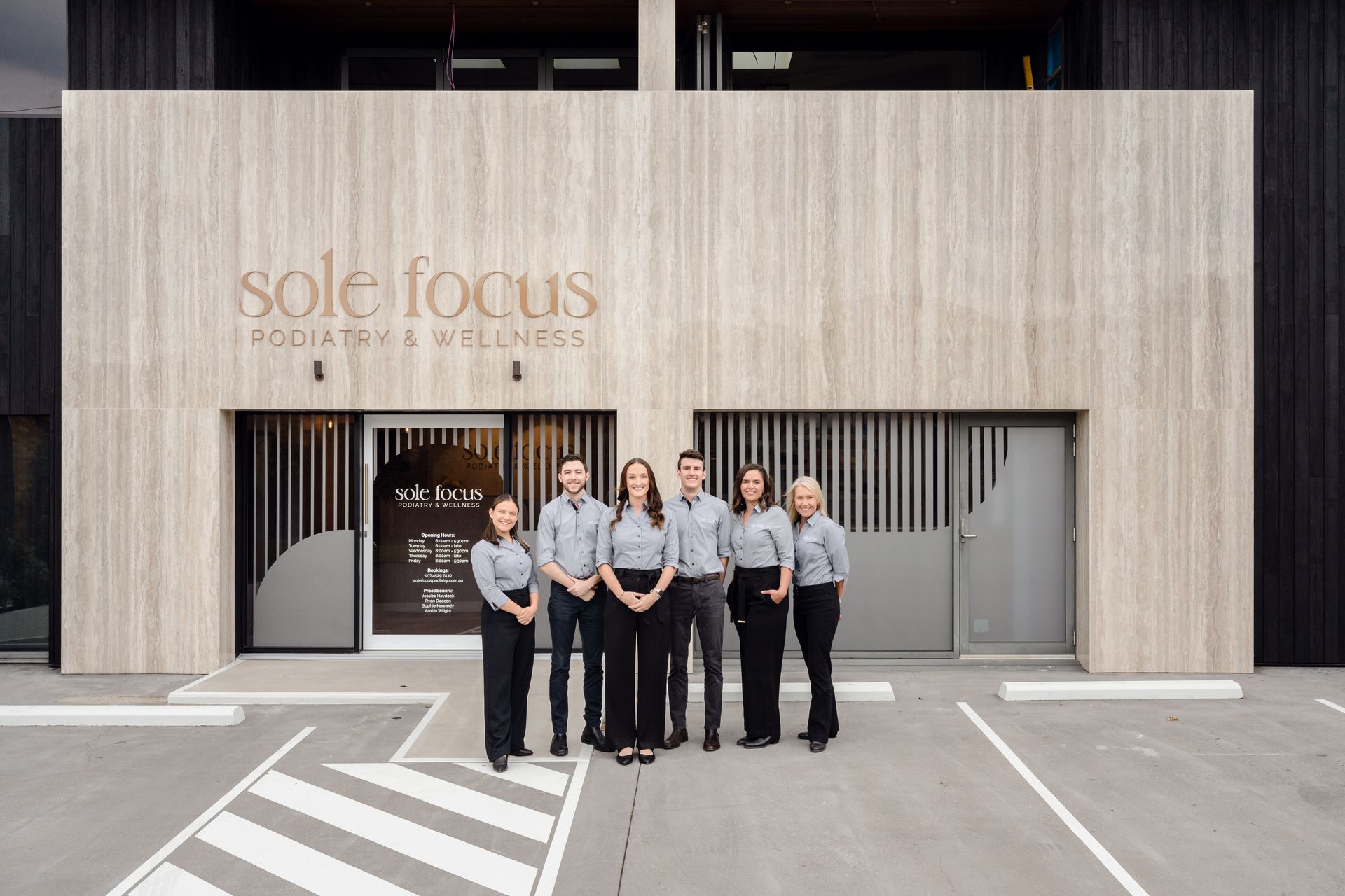Five staff standing outside the Sole Focus storefront, posing in front of a beige building.